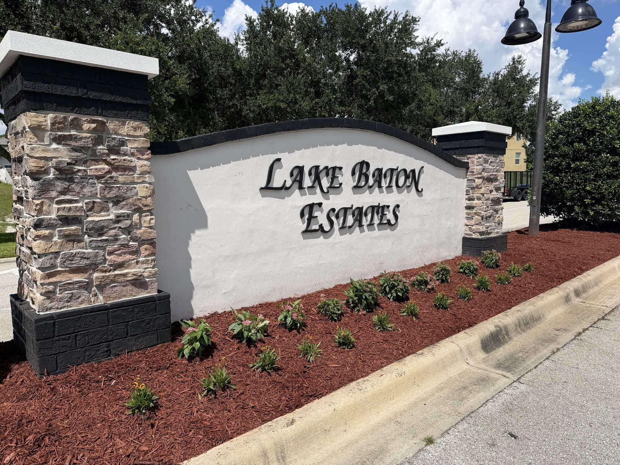Freshly mulched community entrance bed with new plantings around a monument sign