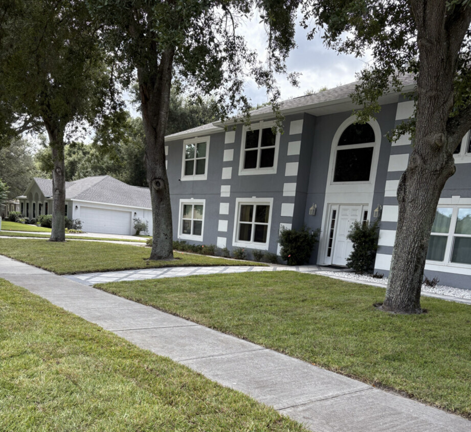 Freshly installed St. Augustine sod along a sidewalk in front of a two story home