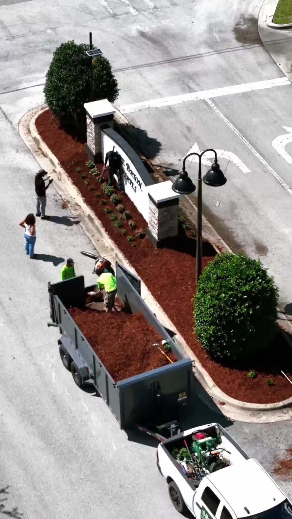 Aerial view of a freshly mulched and planted landscape bed at a community entrance