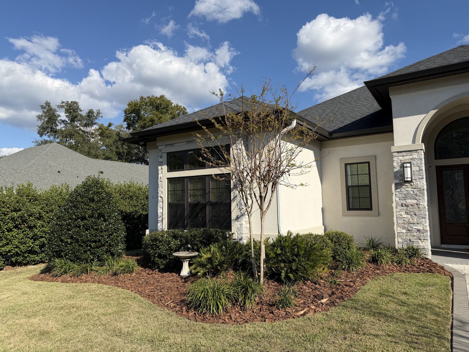 New mulch bed with trimmed shrubs along the side of a stucco home